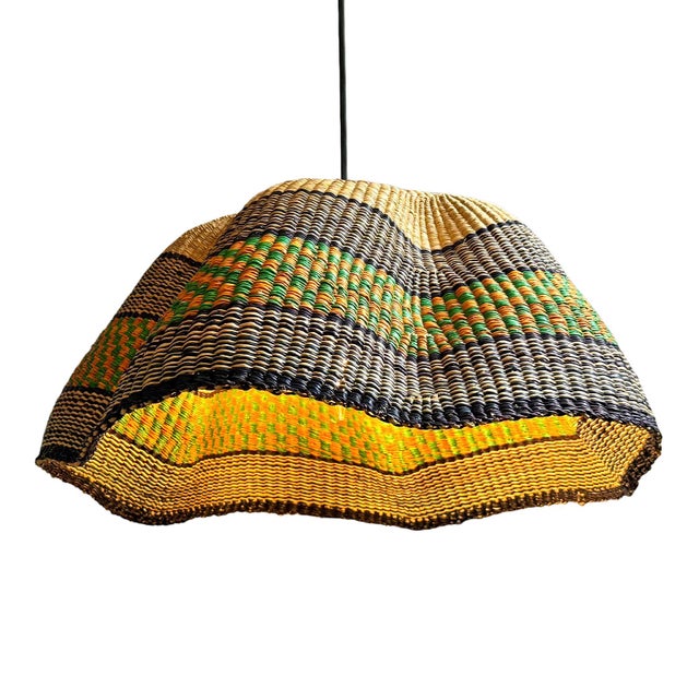 This pendant light began as a traditional Bolga basket from northern Ghana. These baskets were objects of daily use, woven...