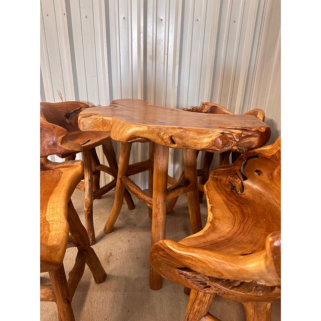 A striking handcrafted rustic dining set featuring a sculptural live edge table paired with four organically carved...