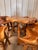 A striking handcrafted rustic dining set featuring a sculptural live edge table paired with four organically carved...
