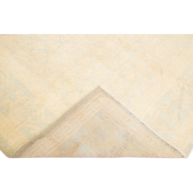 Beautiful modern Khotan tone-on-tone hand-knotted wool rug with a beige field. This piece has light blue accents all over...