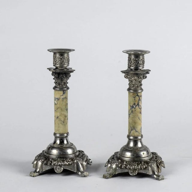 Pair of candlesticks in italian alloy and marble, 1950. They have the appearance of two corinthian columns decorated with...