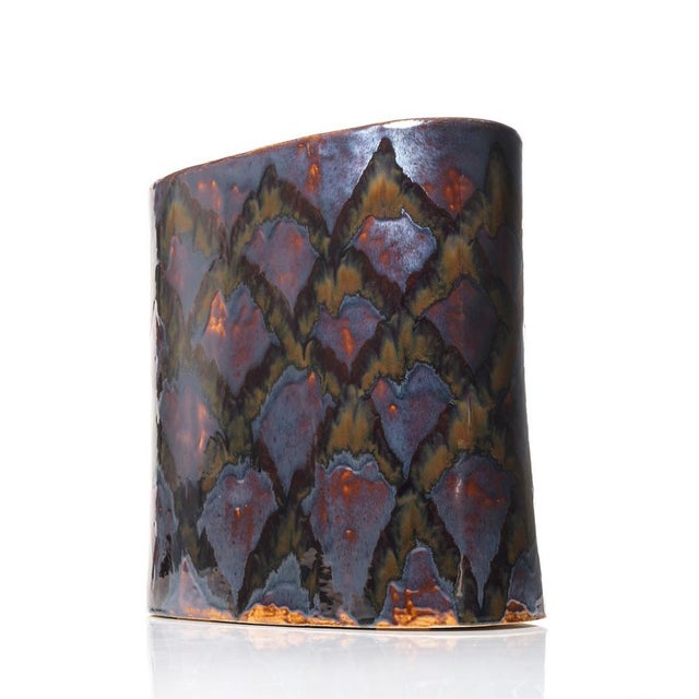 This handmade ceramic side table stands 47 cm tall and features a unique semi-glossy metallic glaze with layered tones of...