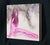 This artwork features a seated figure rendered in a striking interplay of graphite and vibrant pink acrylic on a clay-...