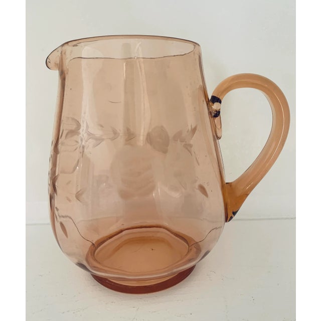 A pink depression glass pitcher with lightly faceted sides and etchings of flowers and leaves. Made to hold your water or...