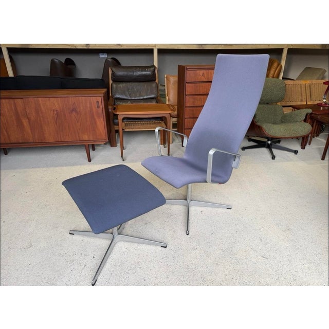 This is a high-back Fritz Hansen Oxford lounge chair and matching ottoman, originally designed by Arne Jacobsen in 1963 is...