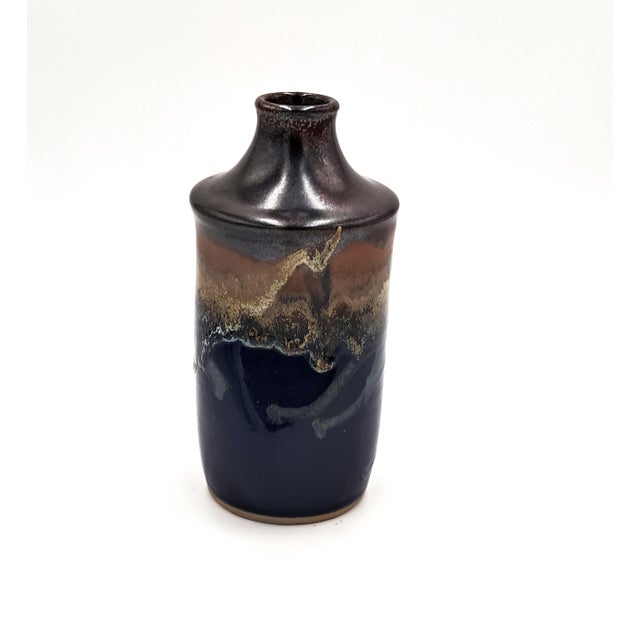 This gorgeous hand-thrown studio vase features a blue base with a shimmering brown at the the top. In between the two...