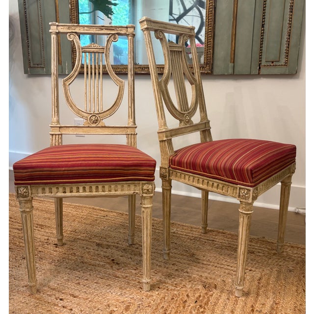 An elegant pair of French Louis XVI revival side chairs executed with carved open lyre-form backs. Versatile chairs that...