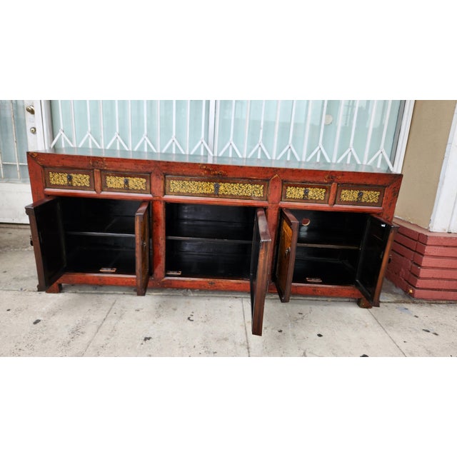 Hand-painted Chinese sideboard is constructed from wood with a distressed red and black lacquer finish. It has five...