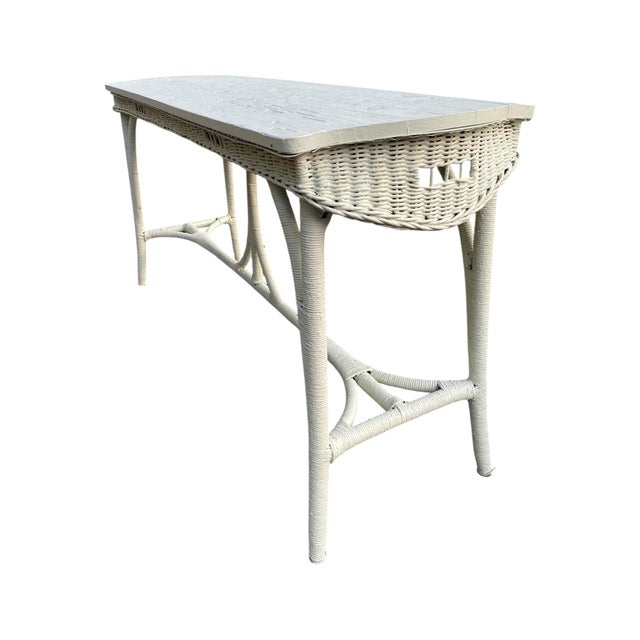 Originally brown, this Victorian wicker console has been hand-painted in a color called seaglass — a faint, quiet celadon...