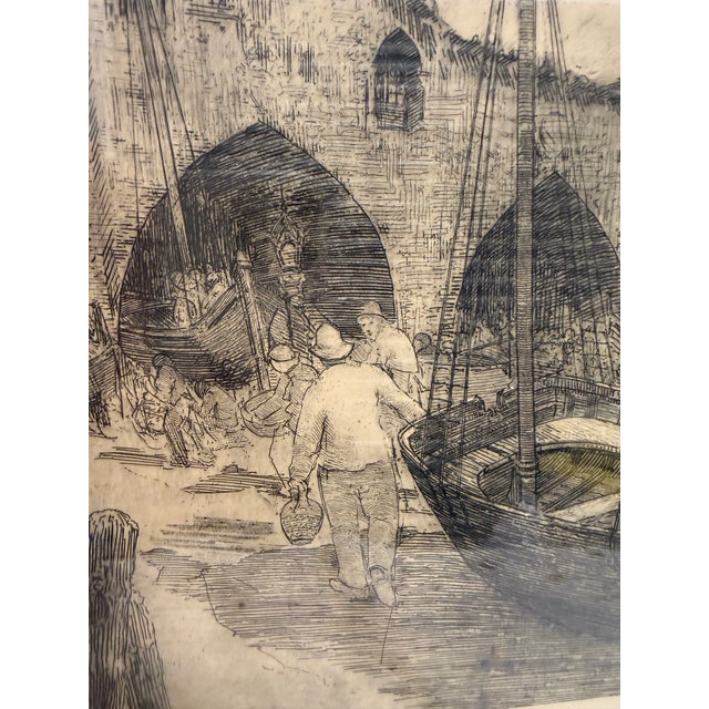 A beautifully detailed vintage etching depicting a bustling Old World harbor scene, with figures moving along the...