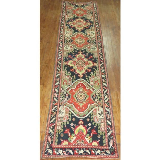 An early 20th century Russian Karabagh runner, predominant accents in red, yellow, and green on a black colored field and...