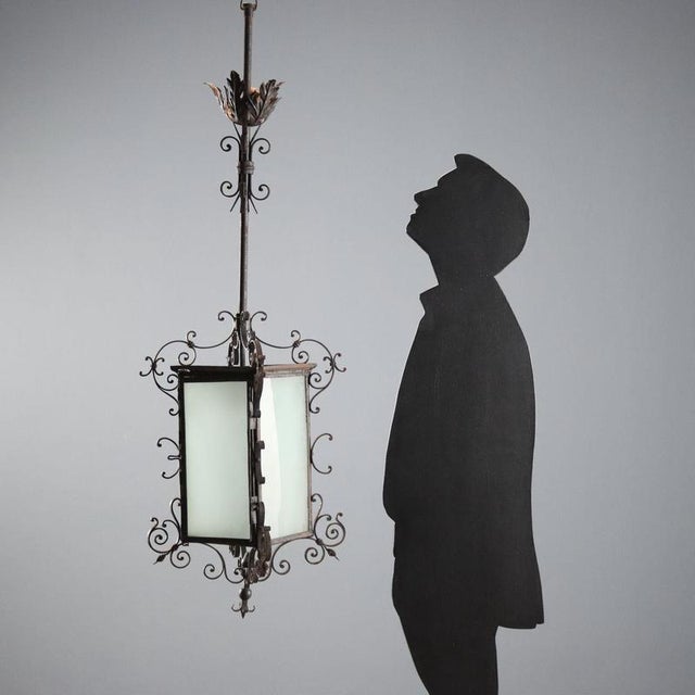 Wrought iron lantern chandelier featuring an elegant design of curls and volutes, typical of early 19th-century Italy. It...