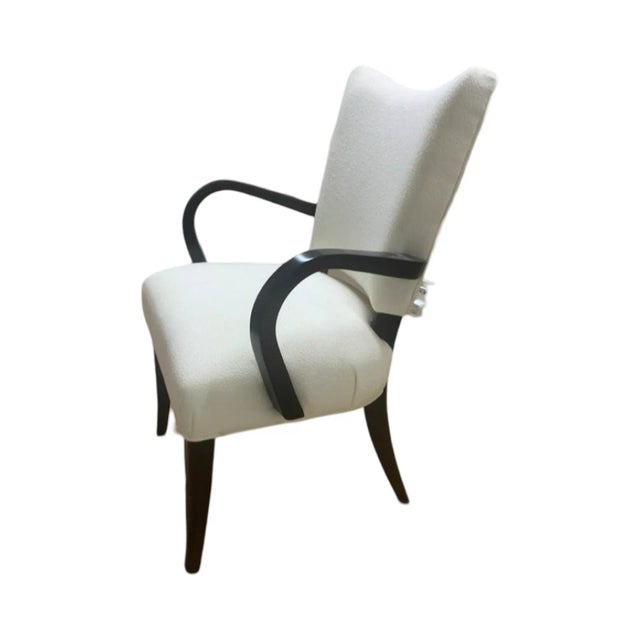 This is the Root Beer Chair by Brueton. It has a cream upholstery with black legs and arms. The frame is made of hardwood...