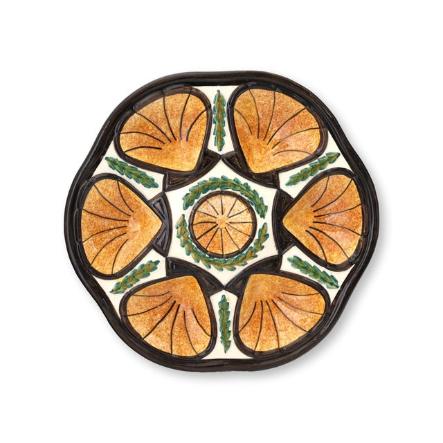 Mid 20th century French majolica oyster plates featuring a vibrant orange and black palette with molded shell wells and...
