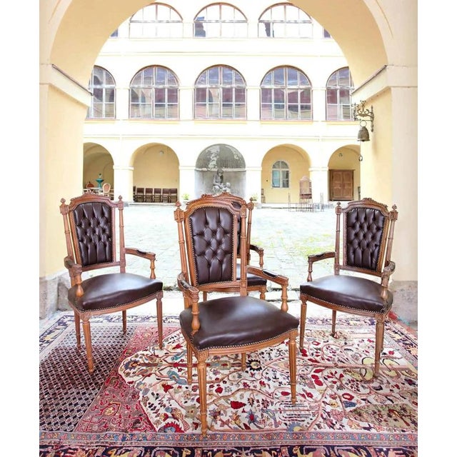 Four armchairs made of solid oak, carved and turned in the Louis XVI style. The upholstery is made of imitation leather....
