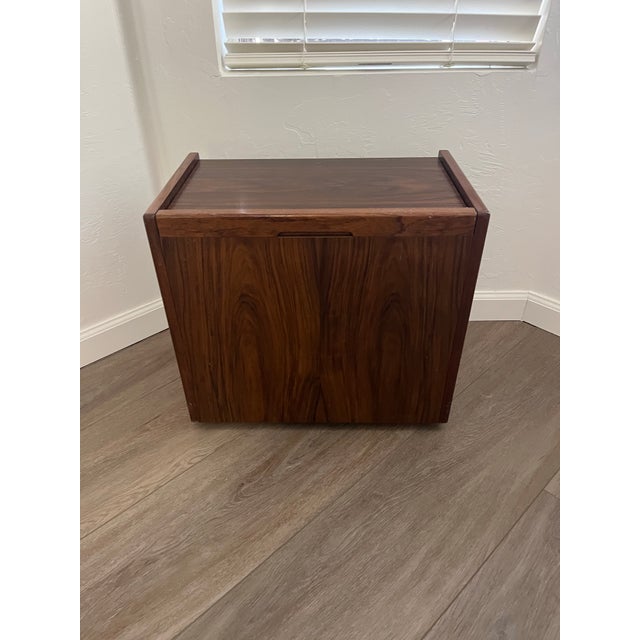 This is a mid-century modern vanitystorage ottoman featuring a dark rosewood base and a beige boucle fabric cushion. This...