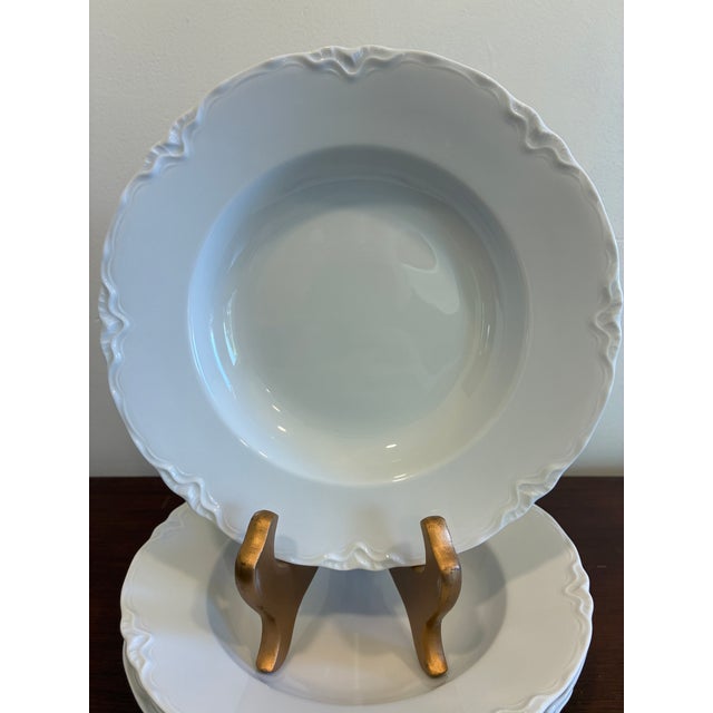 A timeless set of vintage Hutschenreuther Bavaria white porcelain soup bowls featuring softly sculpted decorative rims and...