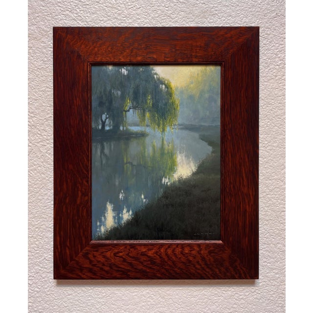 This oil on board artwork captures a tranquil river scene shrouded in early morning mist, where soft hues of blue and...
