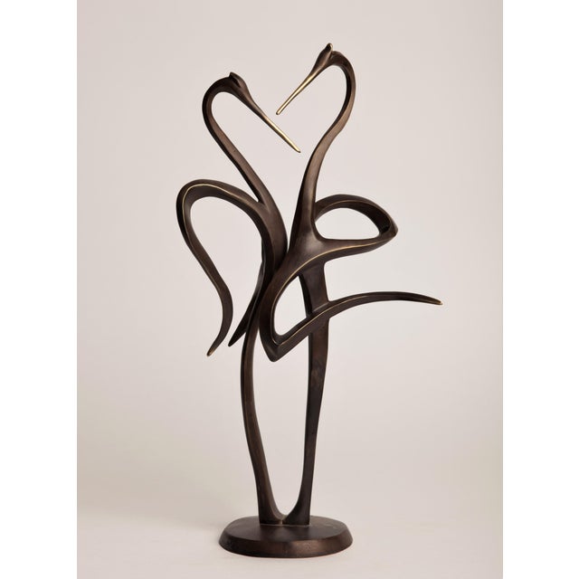 A contemporary animal bronze of two storks, their long necks curving toward one another so the negative space between them...