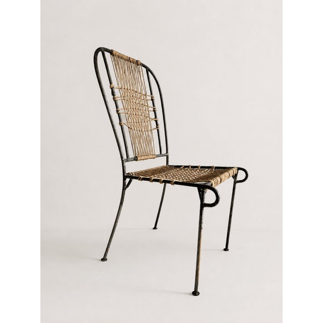A striking set of four mid-century French patio or garden dining chairs crafted from elegant black-painted wrought iron...