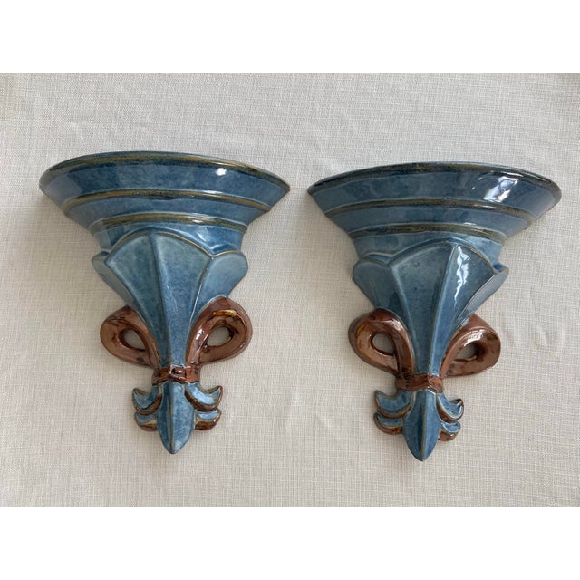 Offered is a stunning pair of vintage ceramic architectural wall brackets. These showcase a prominent central fleur-de-lis...