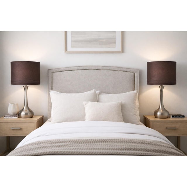 A sleek and versatile pair of contemporary brushed nickel table lamps featuring sculptural tapered stems and original...