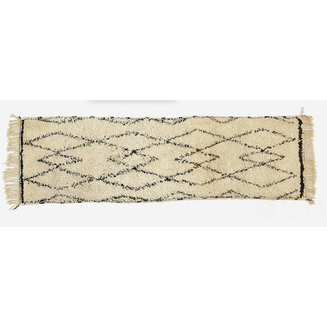 Handwoven Moroccan wool runner featuring a classic black-on-ivory diamond pattern. Soft, plush texture with fringed ends....