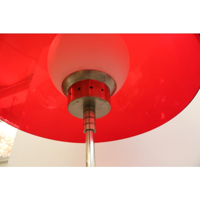 Italian Modernist floor lamp. Red plastic shade merged with metal decorative elements and interior frosted glass globe....