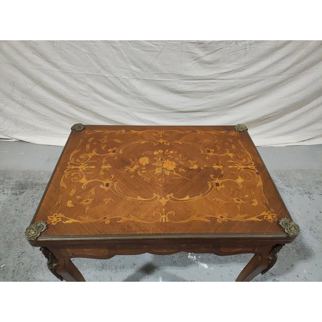 Elegant French Louis XV style marquetry game table dating to circa 1900. This beautifully crafted piece features a floral...