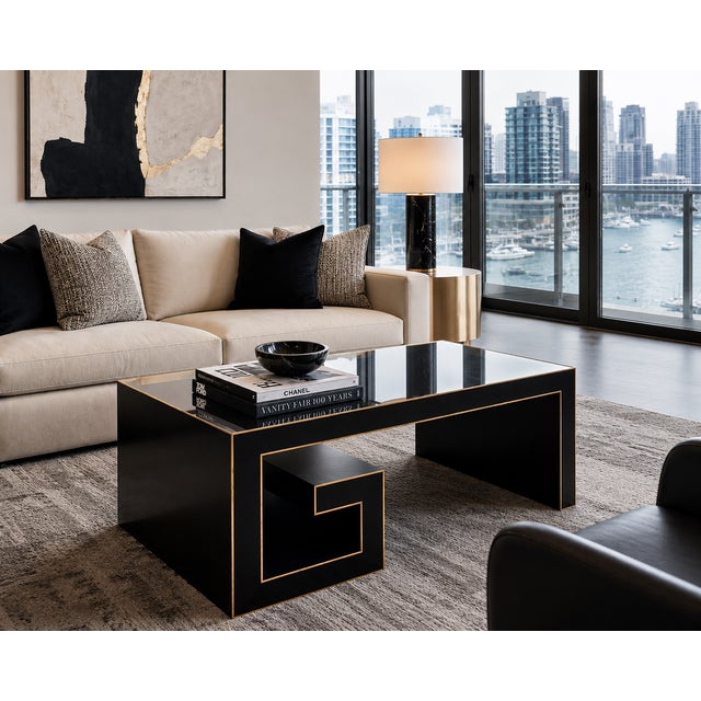 A striking modern coffee table by Currey & Company, featuring a sculptural architectural silhouette finished in rich black...