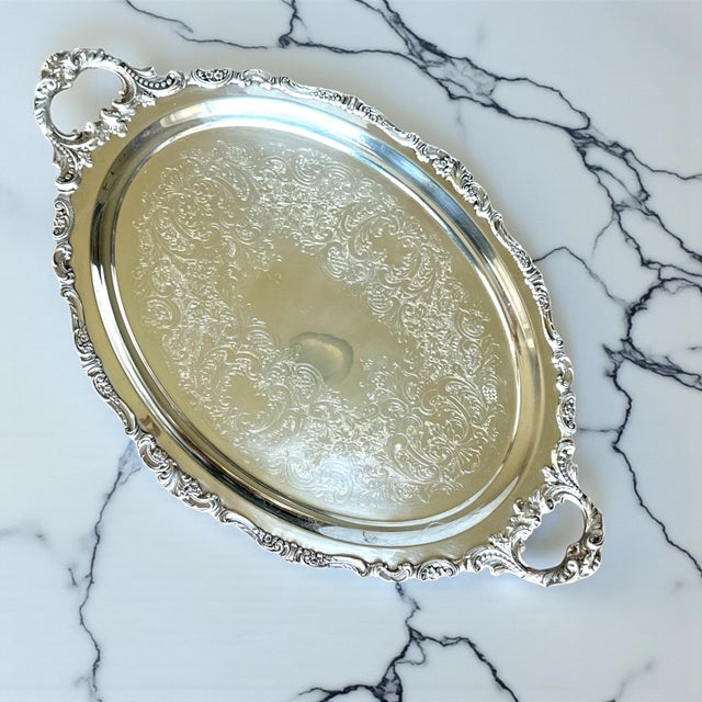 A grand Wallace “Baroque” silverplate butler’s tray, richly decorated in scrolling rococo motifs and standing proudly on...