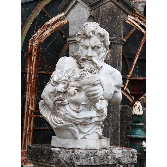 This impressive white marble bust depicts the mythical figure of Hercules, shown holding the head of the Nemean Lion. A...