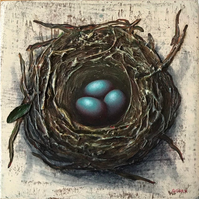 This mixed media piece presents a meticulously crafted bird's nest cradling three vibrant blue eggs, inviting a sense of...