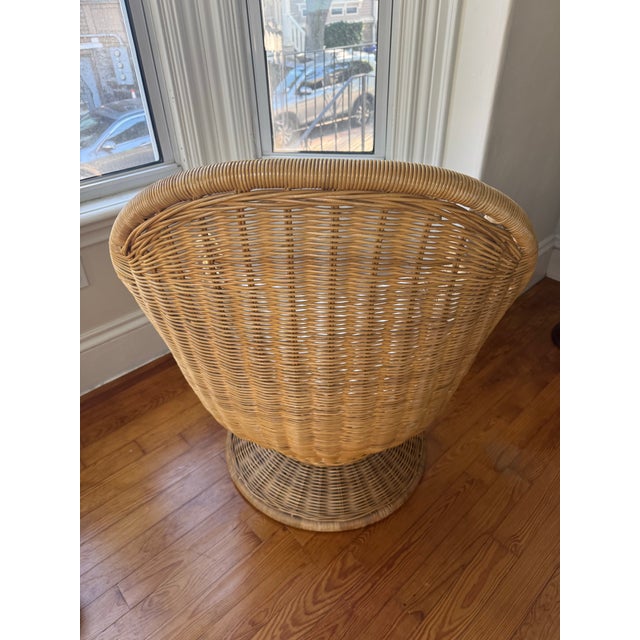 A statement vintage swivel wicker lounge chair with an iron swivel mechanism underneath.