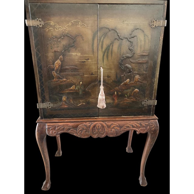 A chinoiserie cabinet on a carved cabriolet leg base with ball and claw feet. The base is very European looking. The...