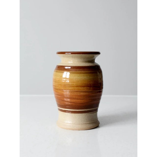 This is a vintage studio pottery vase. The hand-crafted ceramic vase is cream with a brown ombre swirled central glaze...