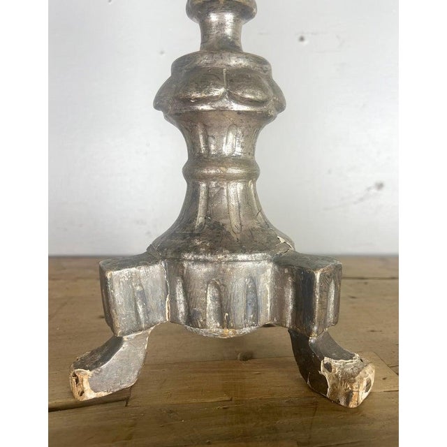 A Pair of 19-century Italian silver gilt candlesticks standing on a tripod-footed base with iron prickets that represents...