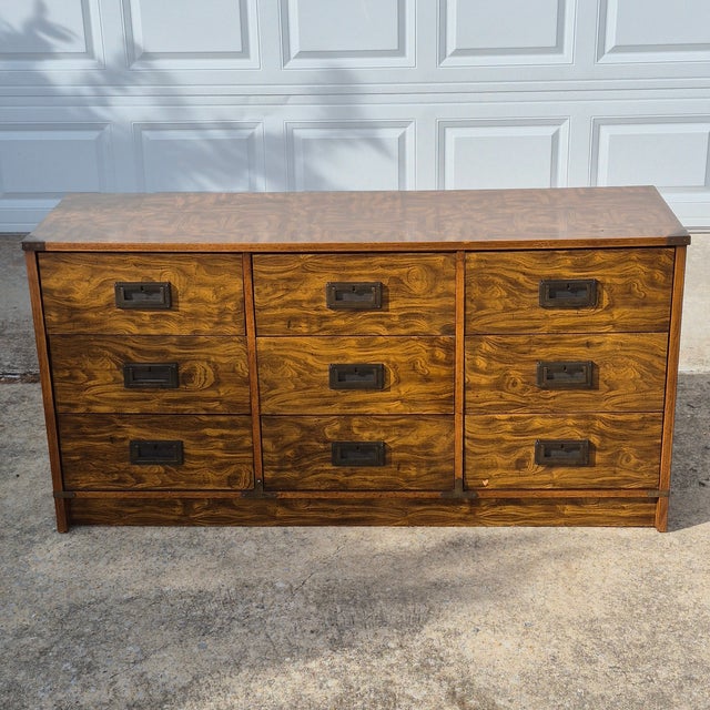 This is a vintage campaign style 9-drawer dresser made of a mix of wood and engineered wood clad in wood-tone laminate....