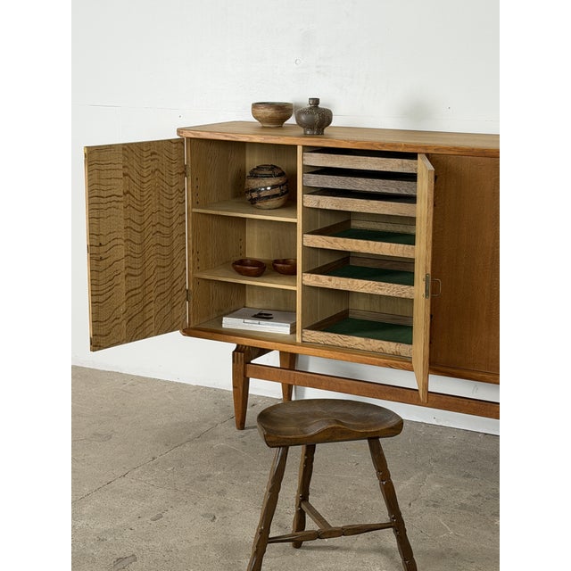 Danish Mid-Century Modern sideboard in oak and brass by Henning Kjærnulf, dating from the 1960s. The long cabinet has four...