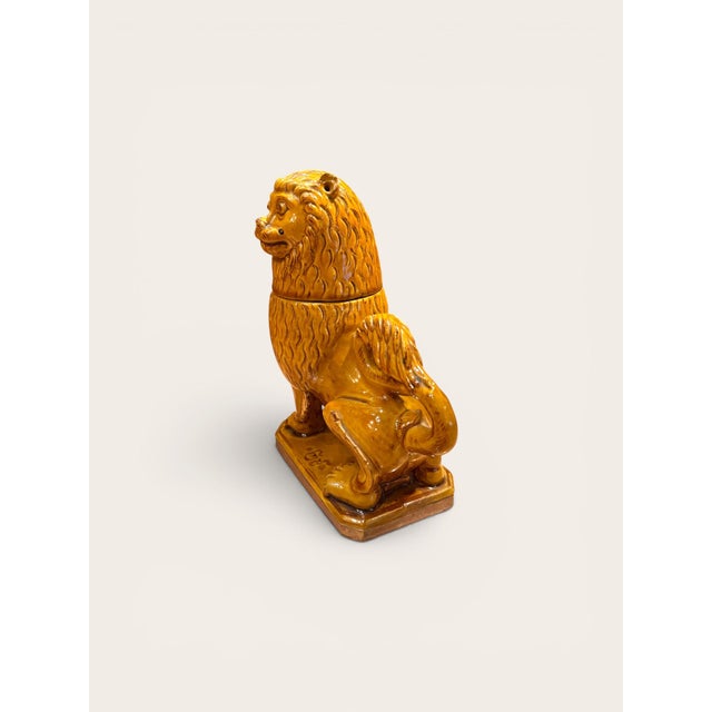 A signed 19th century glazed terracotta lion covered vessel, modeled in a stylized standing pose with an expressive face,...