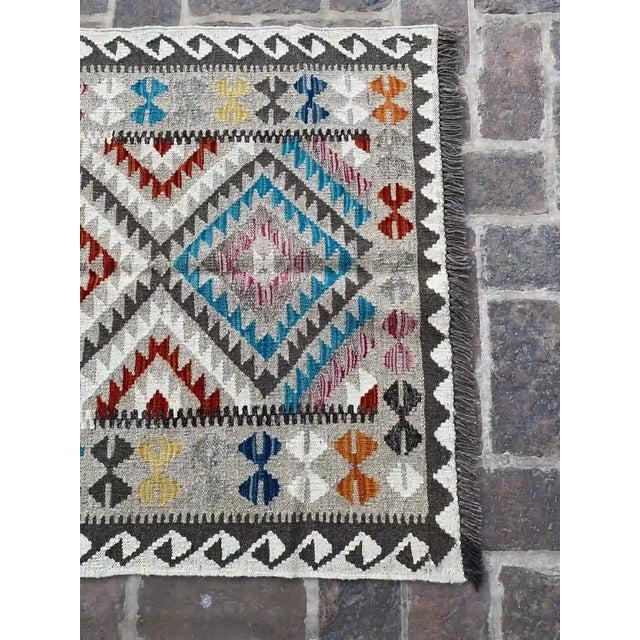 Infuse your home with a touch of bohemian elegance with this handwoven wool kilim rug, featuring a vibrant multicolor...