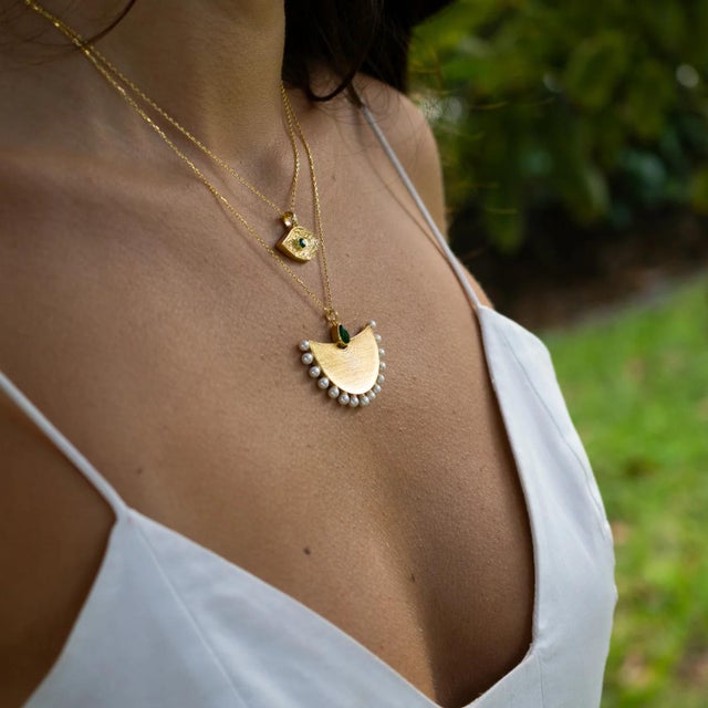 Step into the mystique of ancient Egypt with the Cleopatra Moonlight Emerald & Pearl Gold Necklace, a piece that radiates...