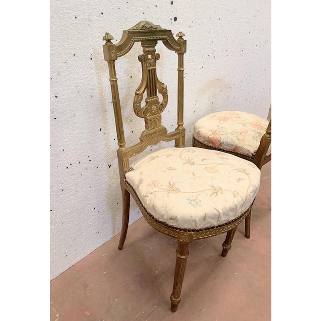 Pair of louis xvi style giltwood chairs four turned, fluted legs lyre-decorated backrests stable chairs one chair is...