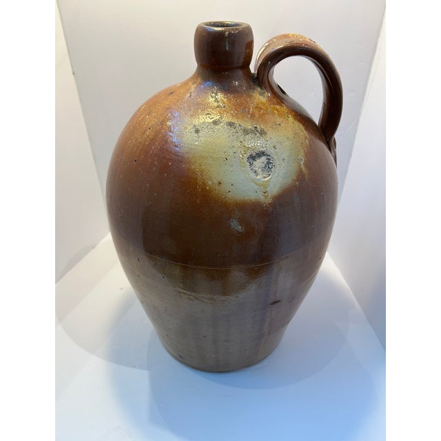 A monumental antique salt-glazed stoneware jug or flagon dating to the 19th century. This substantial hand-thrown vessel...