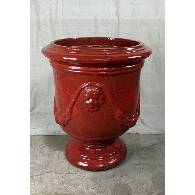 A monumental French Anduze style terracotta garden urn, richly glazed in a deep, lustrous red. The classical form features...