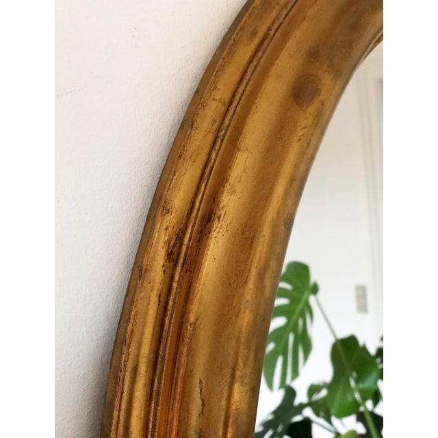 Elegant vintage oval mirror from Belgium, with a carved giltwood frame in a soft gold finish. Object: Mirror Style:...