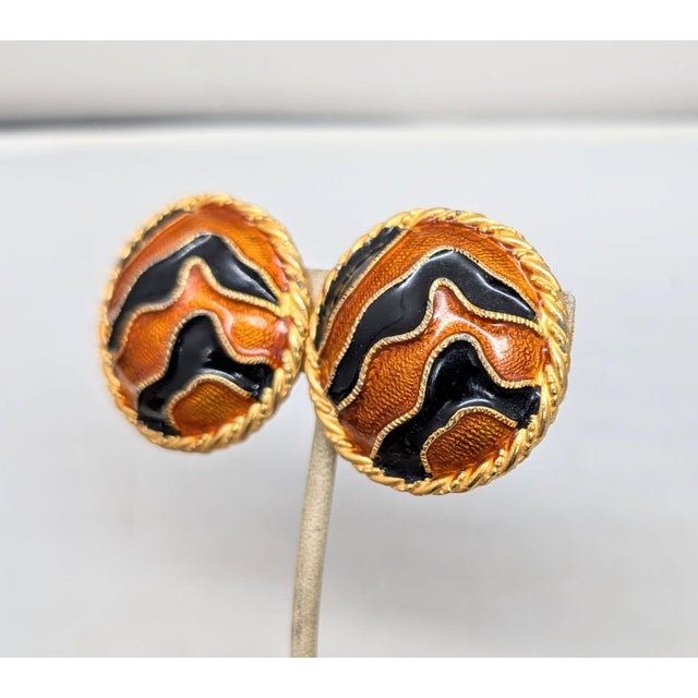 1980s round slightly domed goldtone orange and black striped clip earrings. Marked "YOSCA©" on the backs. Measure: 1 7/16...