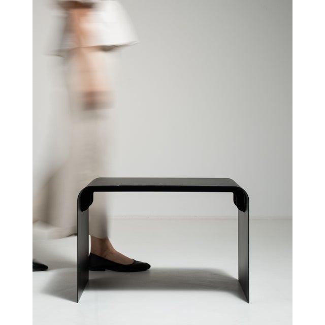 This early 21st century side table from Poland is finished in black, worked in wood. Its form follows honest, well-...