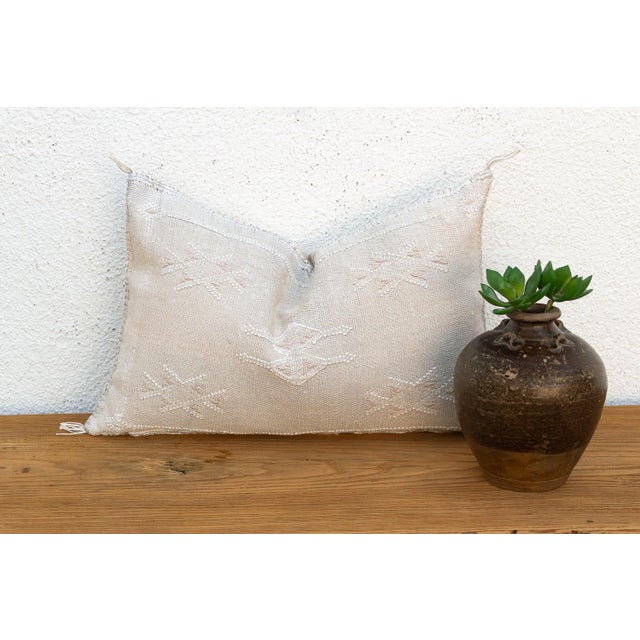 A dense cluster of star motifs radiates near the seam of this handcrafted Moroccan cactus silk lumbar pillow, hand-...