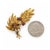 This 18 karat yellow gold brooch from circa the 1950s is designed as a spray of richly textured leaves. Three flowers sit...